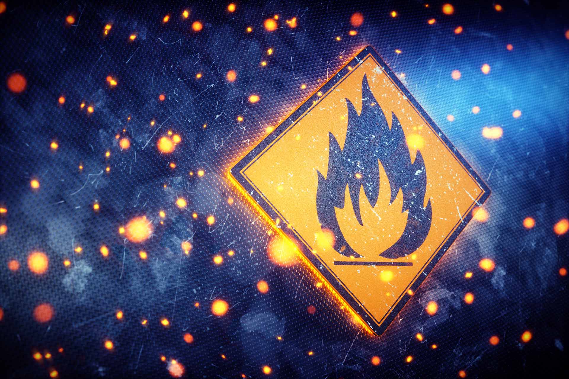 Illustration of an orange diamond warning sign with a black flame symbol on a dark textured surface scattered with glowing embers