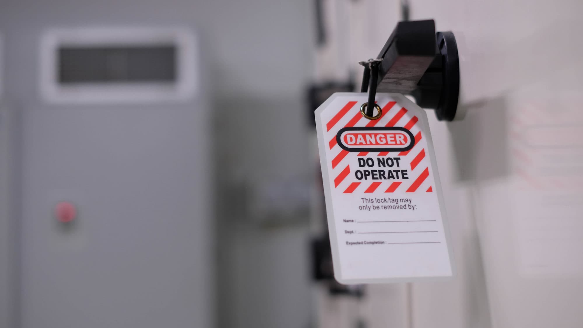 Lockout/tagout tag reading “Danger: Do Not Operate” attached to industrial equipment.