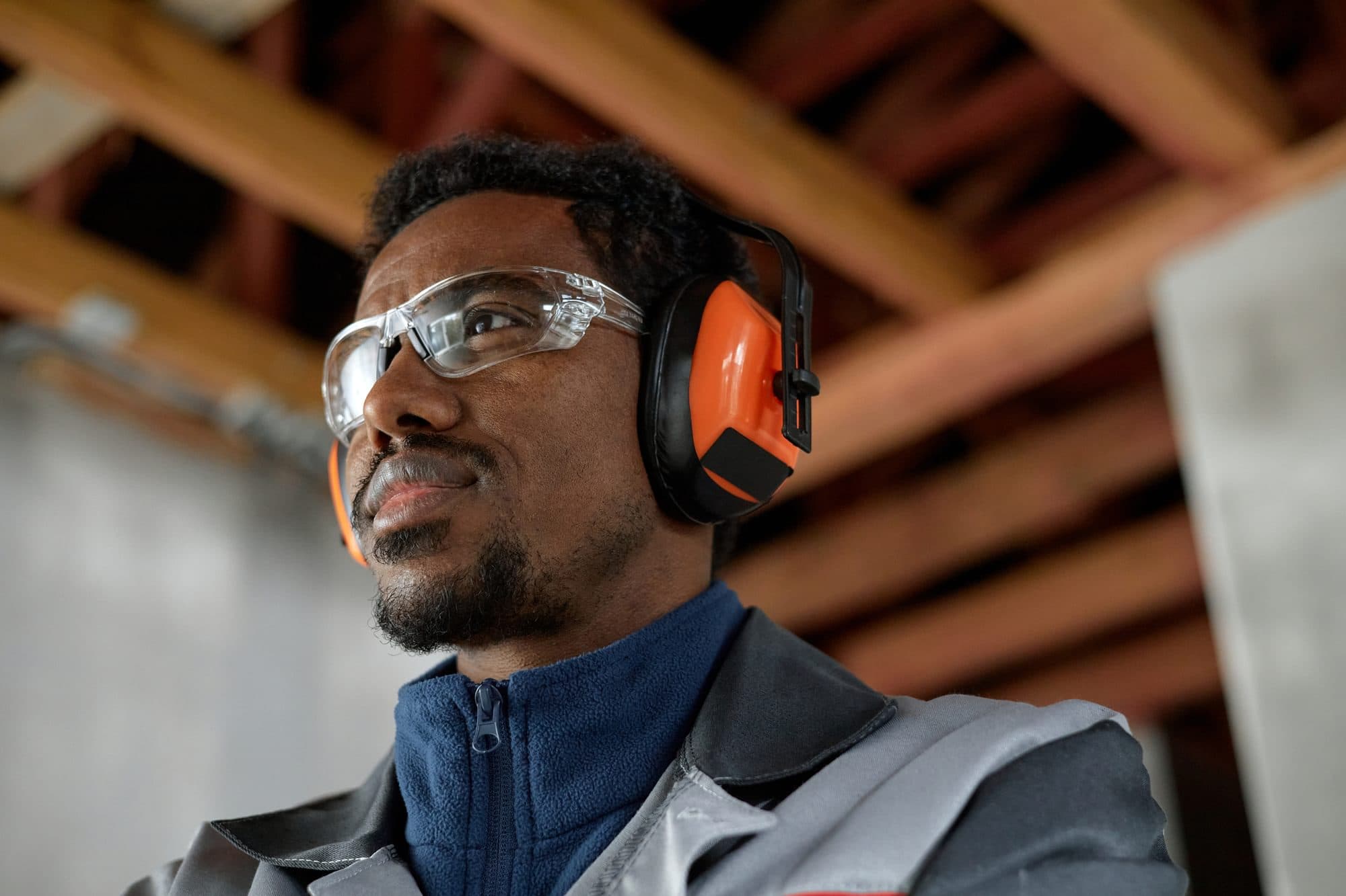 Worker wearing hearing protection and safety glasses in an industrial workplace.