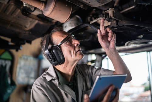 Technician spray painting car with GMG's EHS-compliant collision repair solutions
