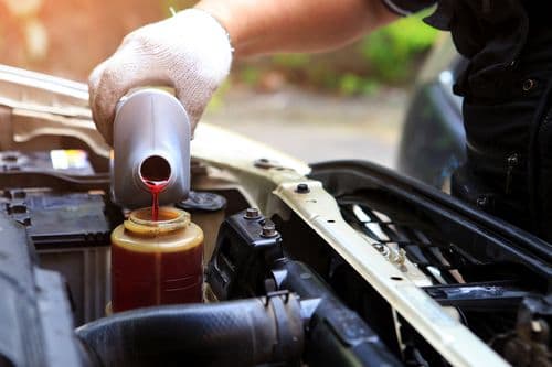 Technician spray painting car with GMG's EHS-compliant collision repair solutions
