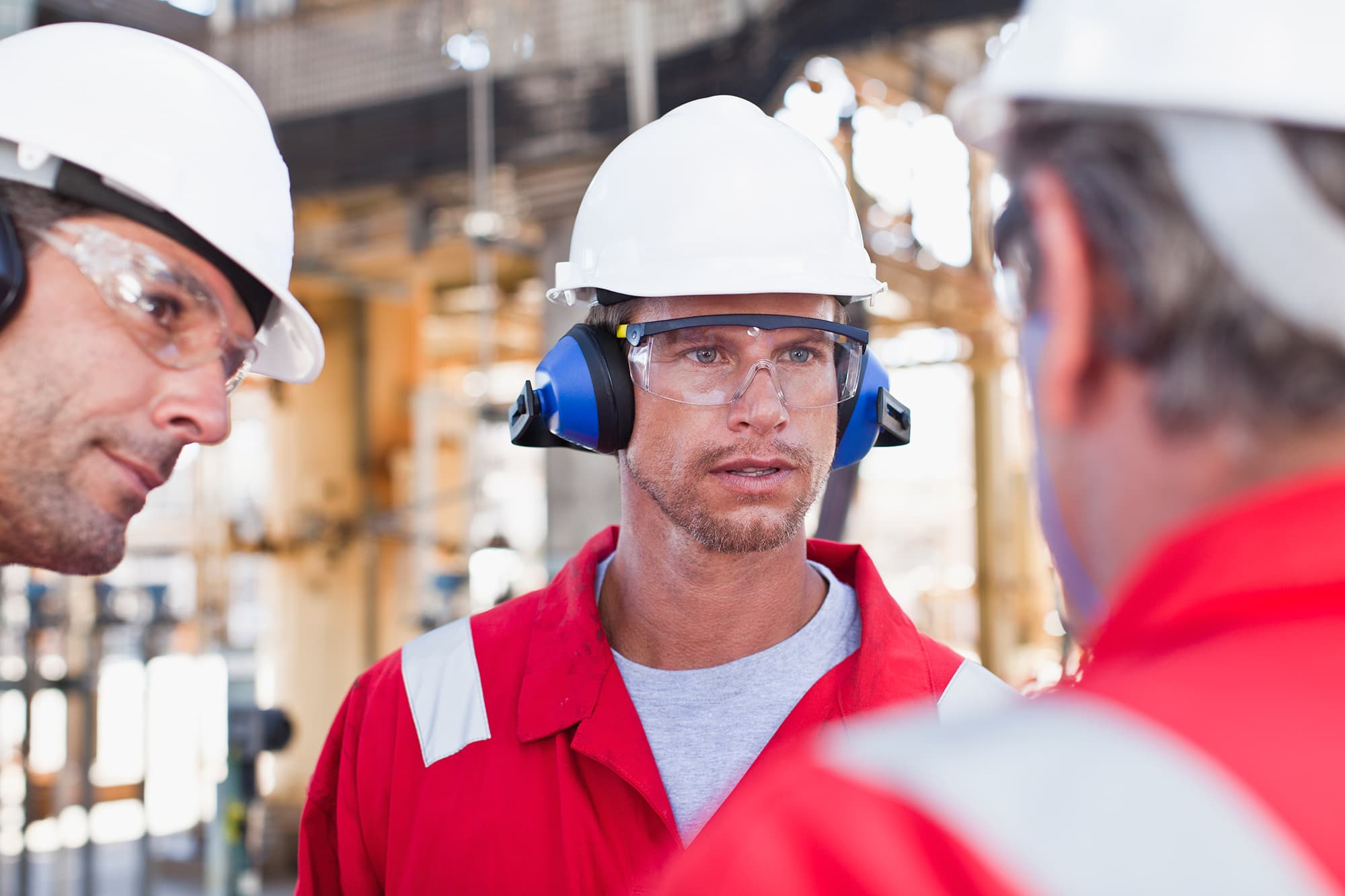 GMG EnviroSafe worker in red coveralls, hard hat and hearing protection on site